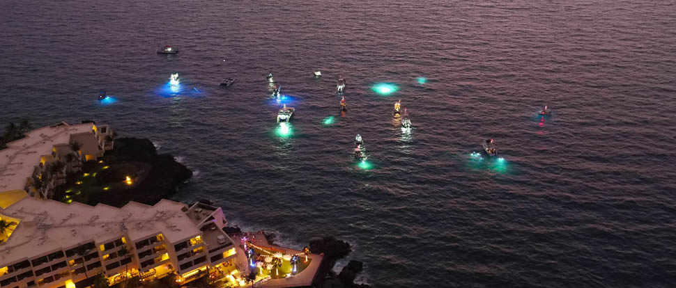 aerial view of the manta ray night snorkel boats at sunset just off the coast. Lights a seen underwater