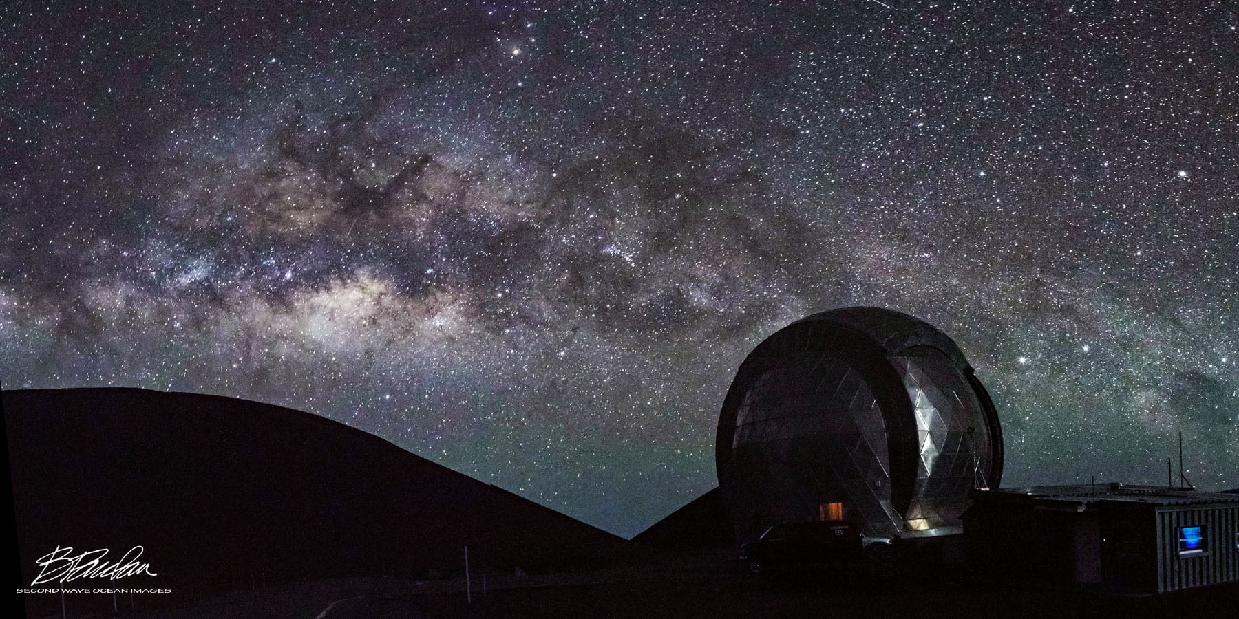 A brilliant and beautiful star field with Milky Way and a telescope dome and mountain hills silhouetted in the foreground