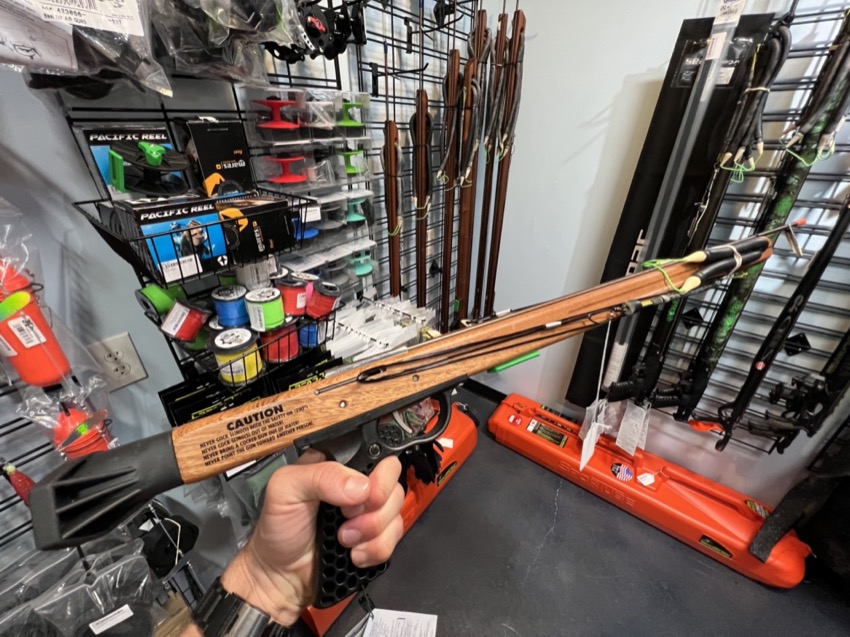 holding a speargun in hand in a dive shop