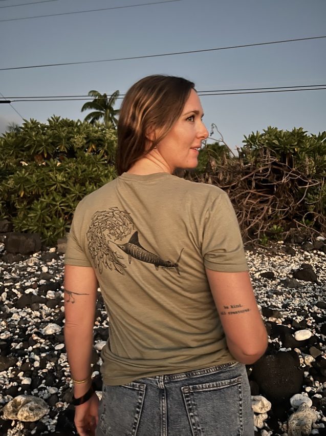 WOMAN wearing olive shirt with marlin chasing school of fish on the back