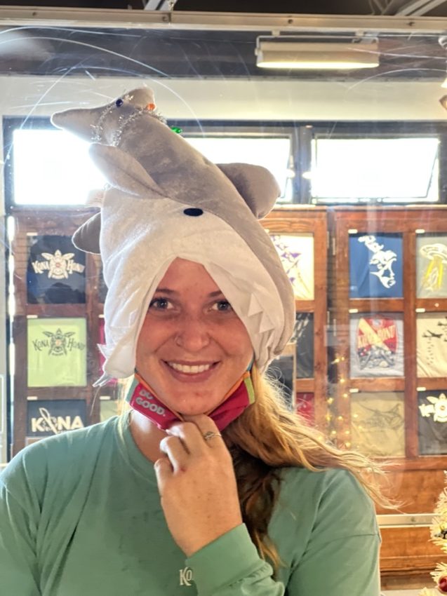dive shop staff ari wearing a shark hat that is eating her head