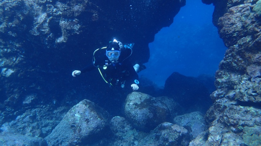diver swimming under cavern