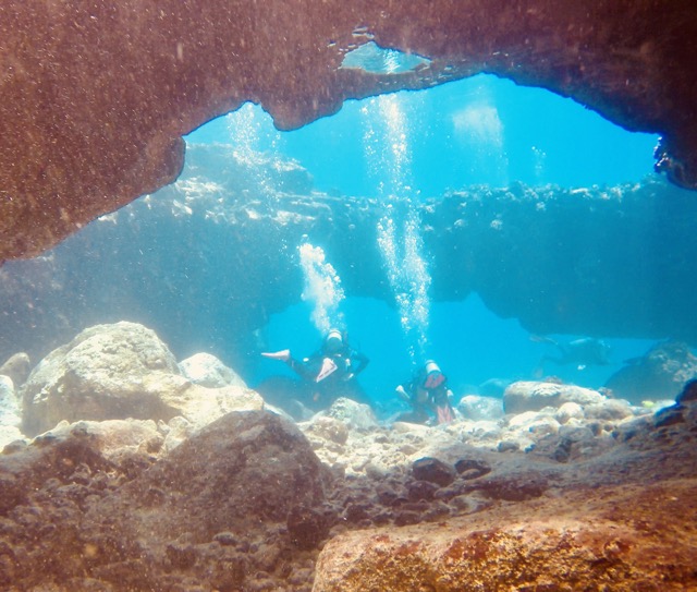 2 divers swim under arches