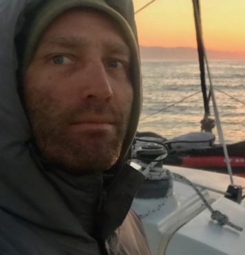 headshot of Justin Moore captaining a sailing yacht