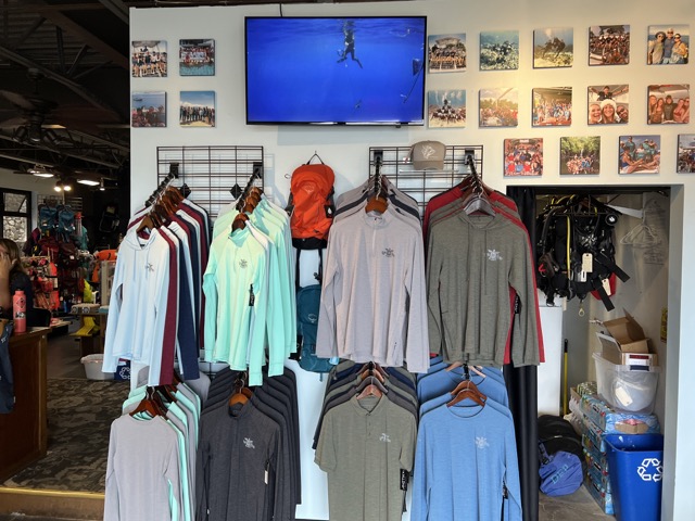 a wall inside a dive shop with sun shirts on display
