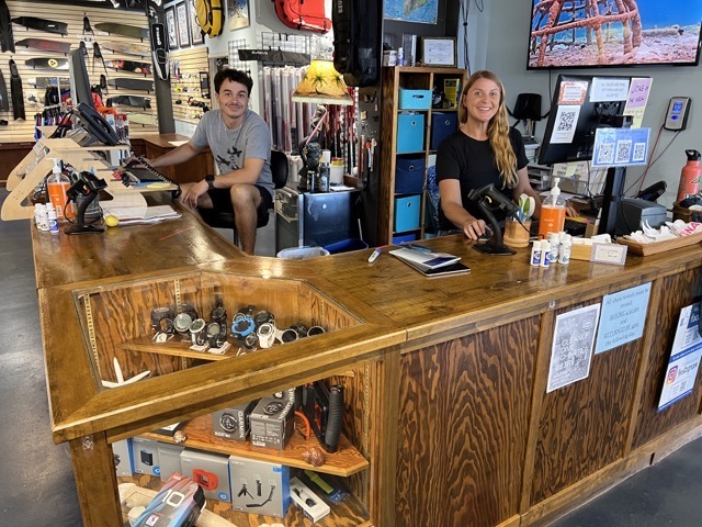 2 people sitting at a front desk  on inside a dive shop