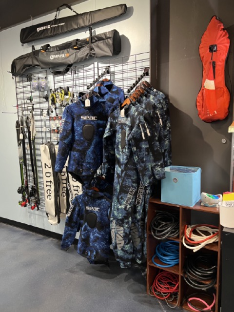 spearfishing products, wetsuits, spearguns and floats are displayed inside a dive shop