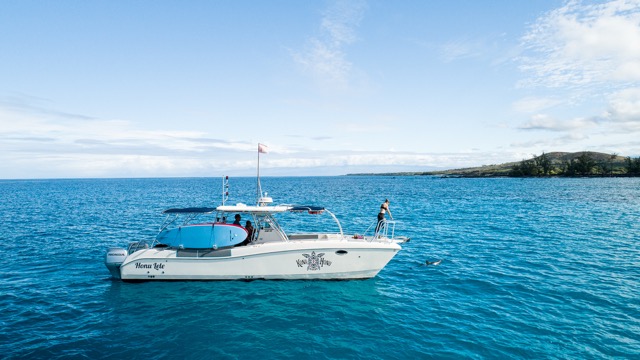 person standing on the bow of a boat looking down toward the water