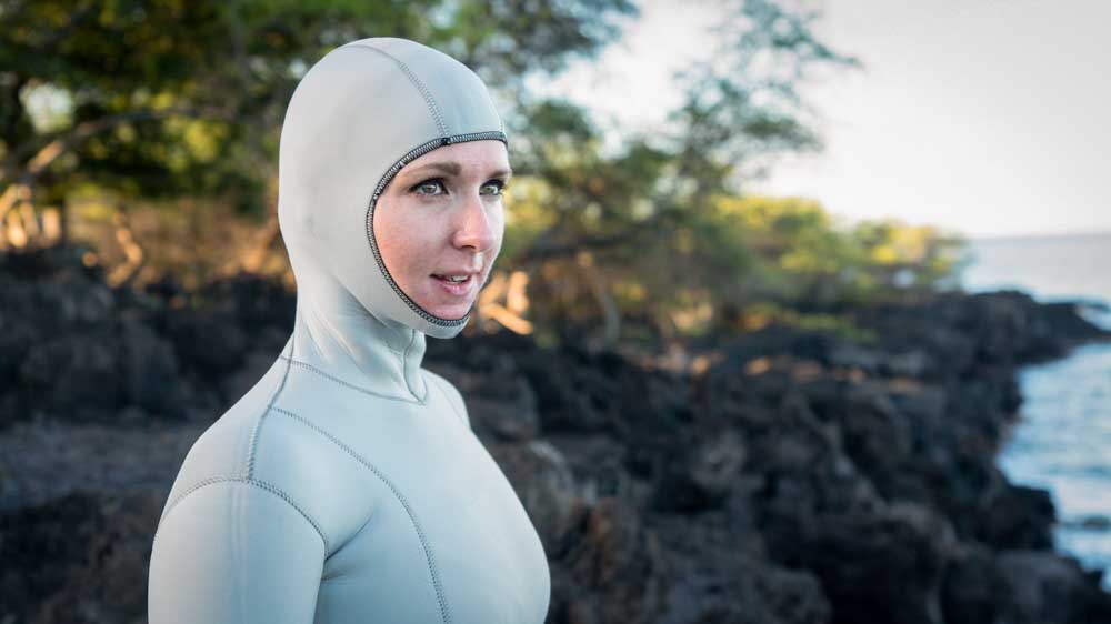 a diver on rocky shore in a freediving full wetsuit