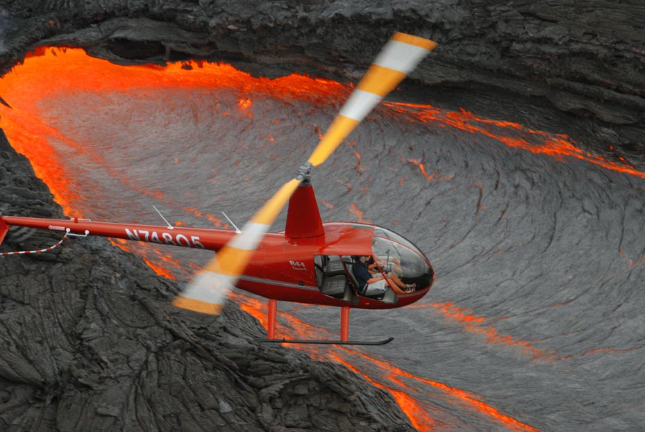 helicopter flying over glowing hot lava flow