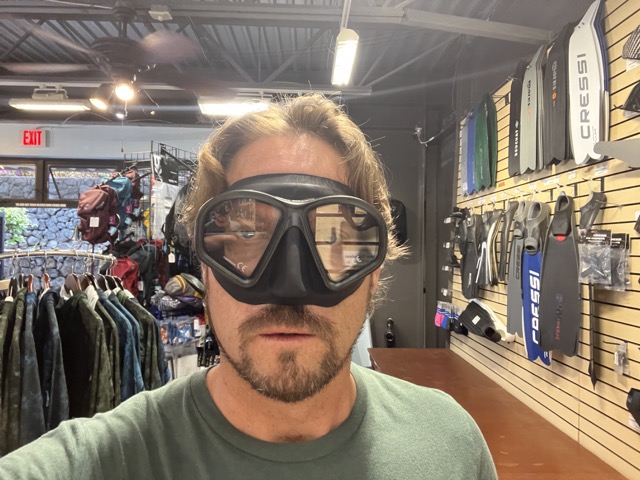 a man wearing a mask stands in a dive shop