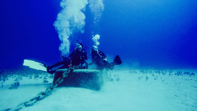 a deep reef mooring block with 2 divers sitting on it