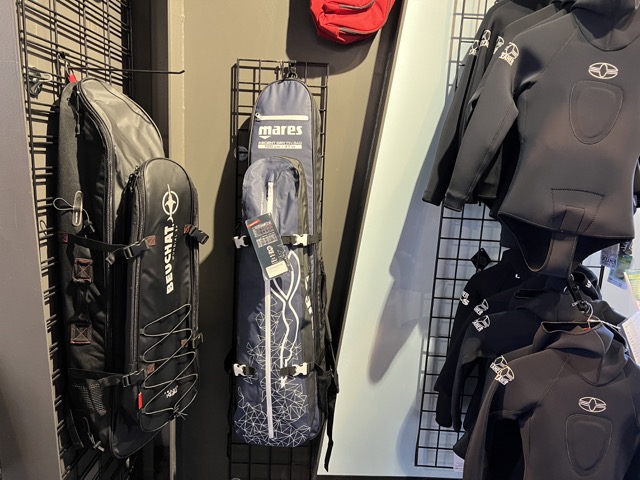 inside of a dive shop are some wetsuits and fin bags