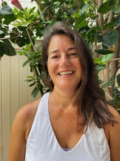 headshot of a caucasian woman with long straight brown hair she is wearing a white tank top and smiling