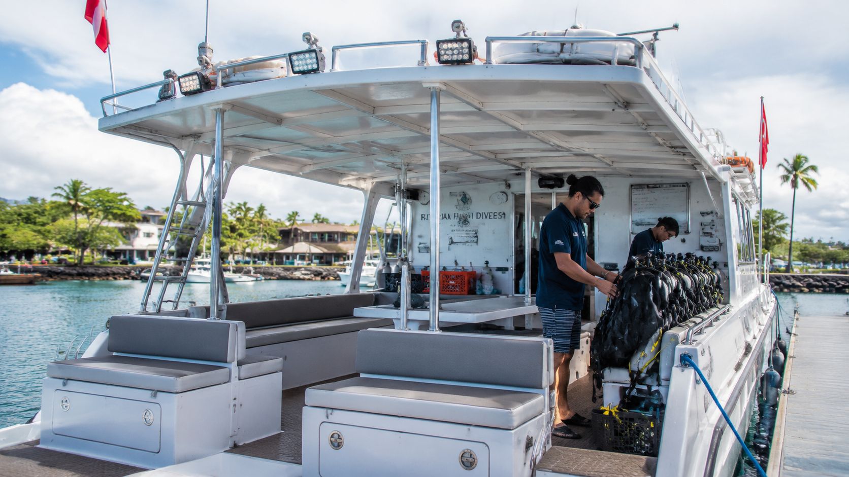 A dive boat crew member prepares diving gear on the deck of a boat in Hawaii.