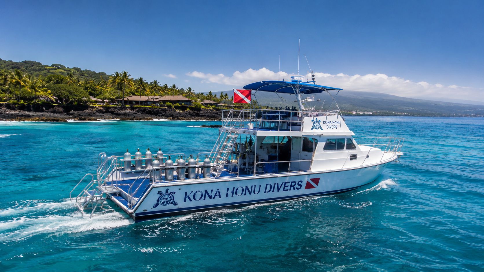 A white Kona Honu Divers scuba diving boat cruising in the bright blue tropical waters of Hawaii.