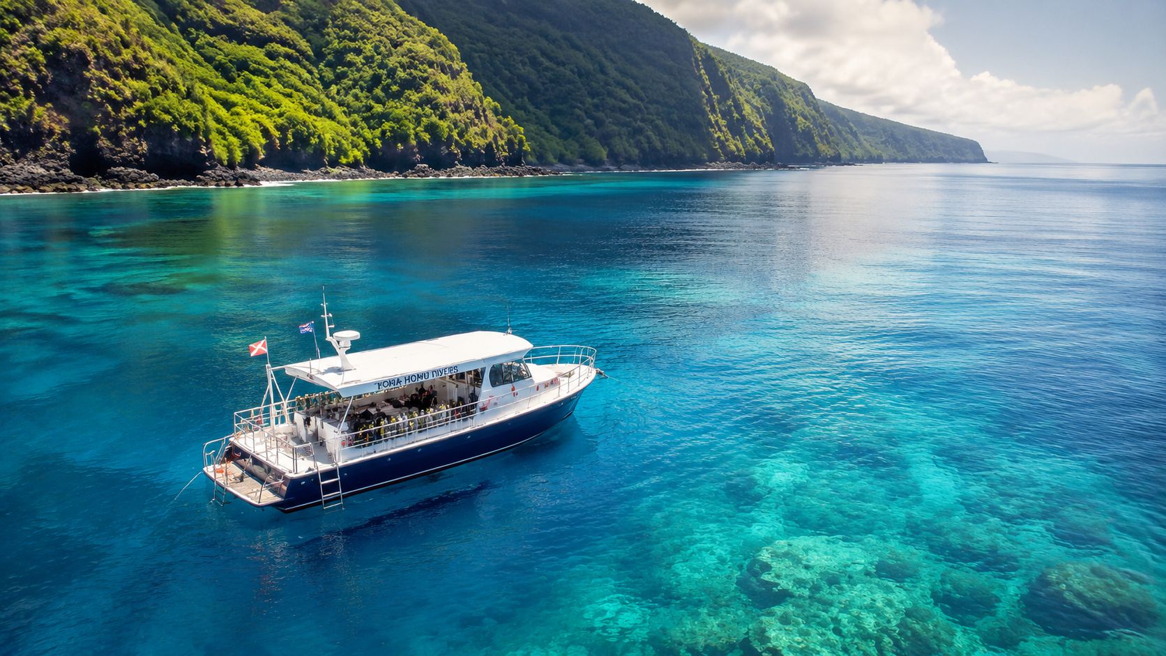 A Kona Honu Divers boat floating on vibrant turquoise water near the lush coastline of Hawaii.