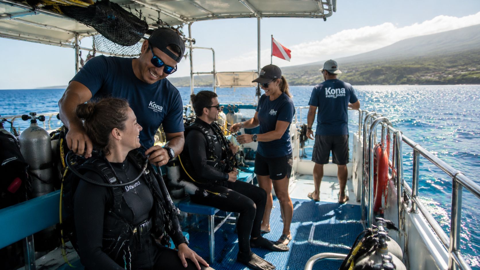 A professional dive instructor assists a student with her scuba gear on a boat in Hawaii.