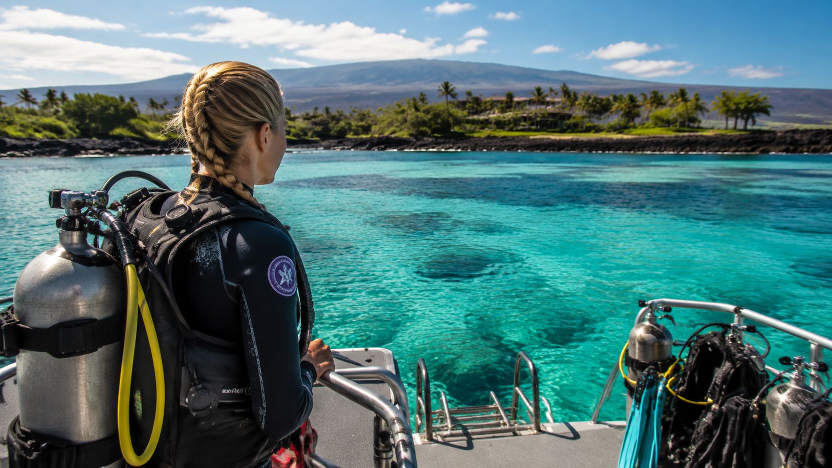 A scuba diver on a boat preparing to dive into the clear turquoise waters in Kona, Hawaii.