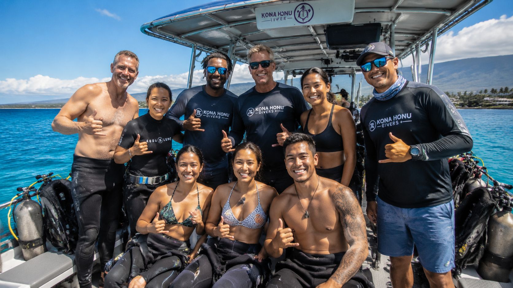 A group of cheerful Kona Honu Divers staff members posing together on a boat at sea.