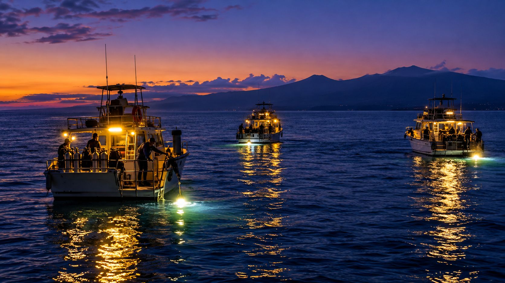 Three boats on the water at sunset preparing for a manta ray night dive in Hawaii