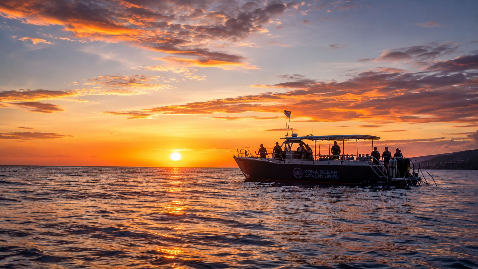 A silhouette of a Kona Ocean Adventures boat against a vibrant orange and purple sunset over the ocean.