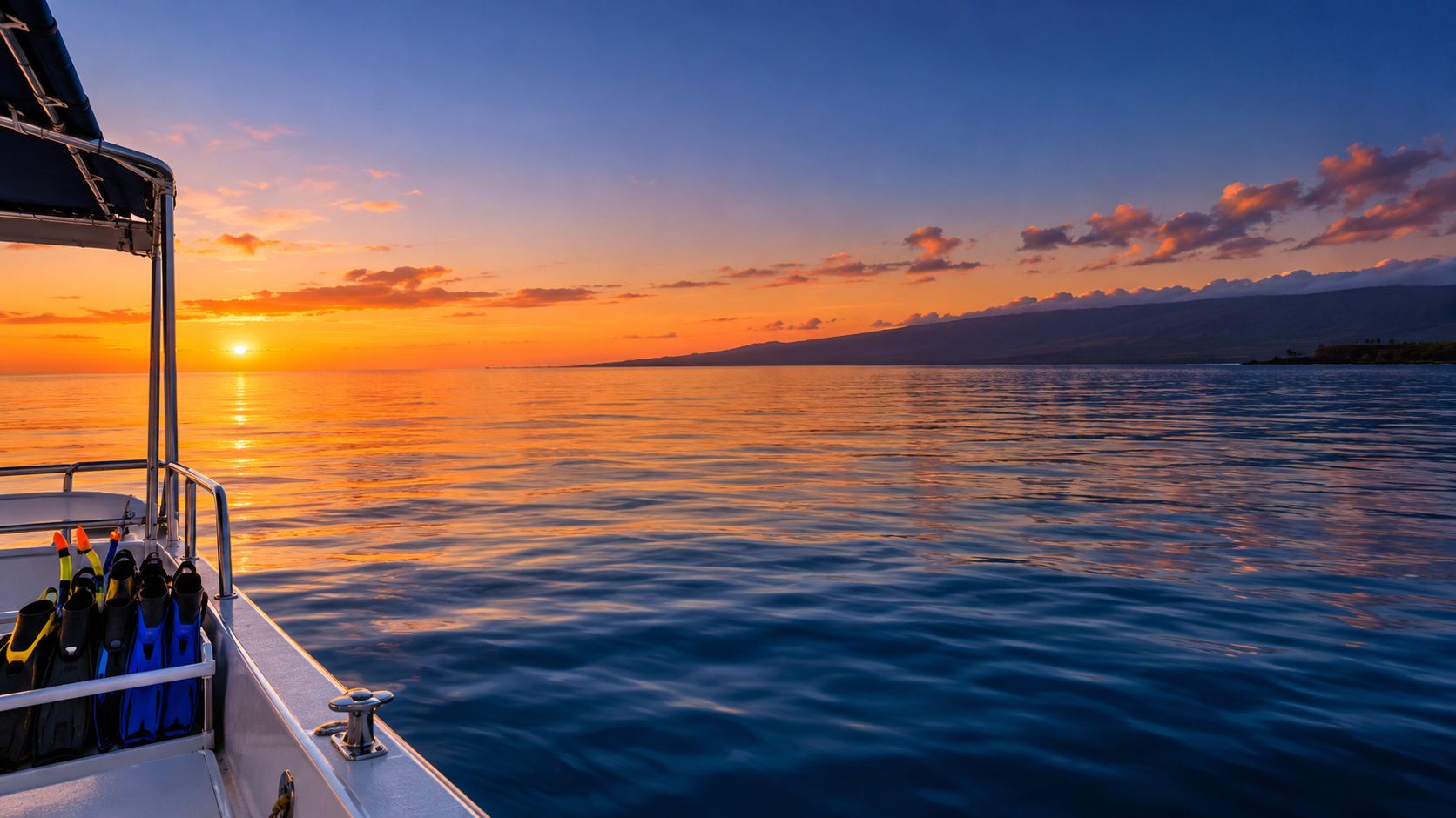 A scenic view from a boat deck during a beautiful golden sunset over the ocean water.