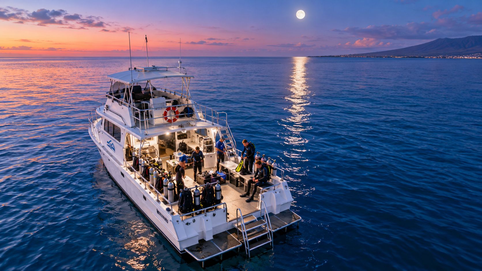 Divers preparing equipment on a boat deck at dusk under a full moon over the calm ocean